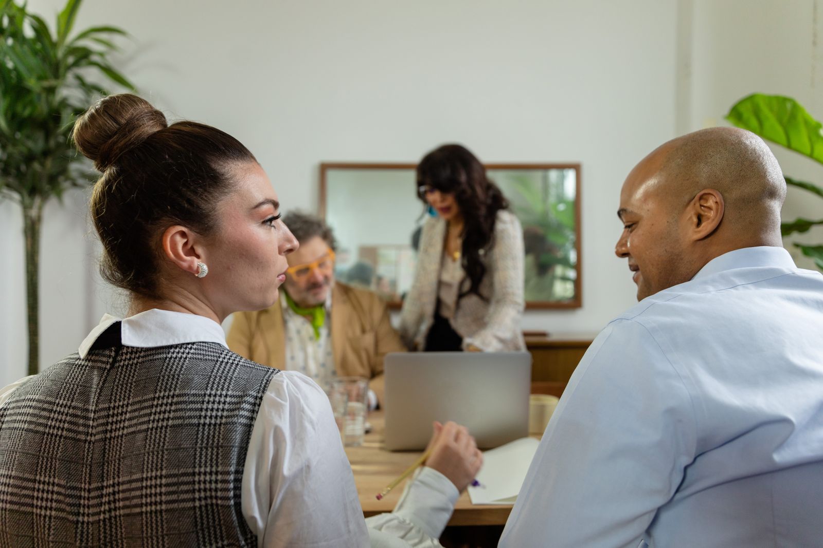 Professionals discussing a project around a laptop in a bright meeting room