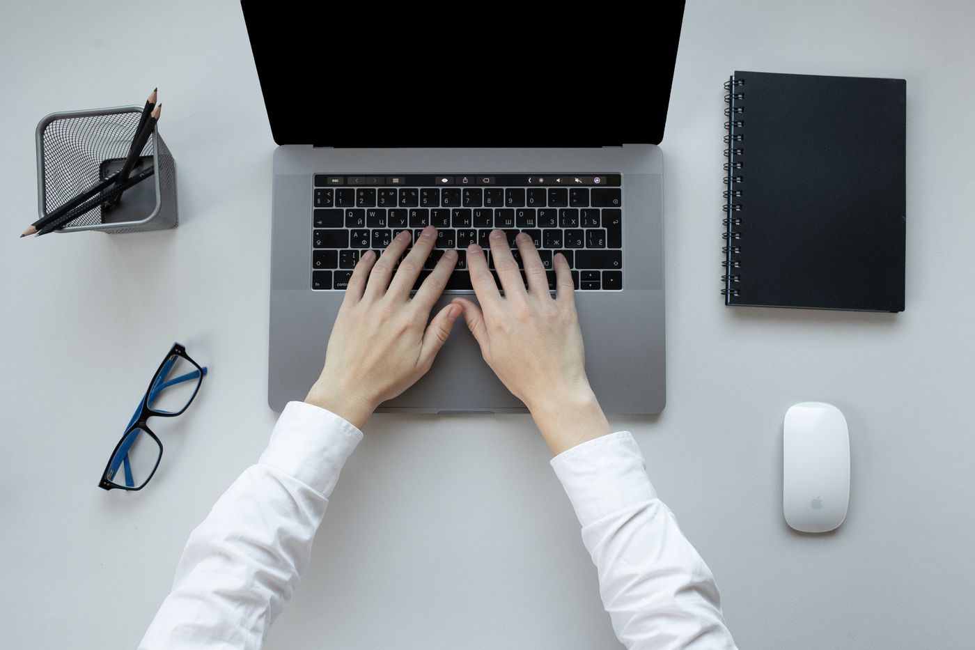 Hands typing at a laptop on a neatly arranged desk