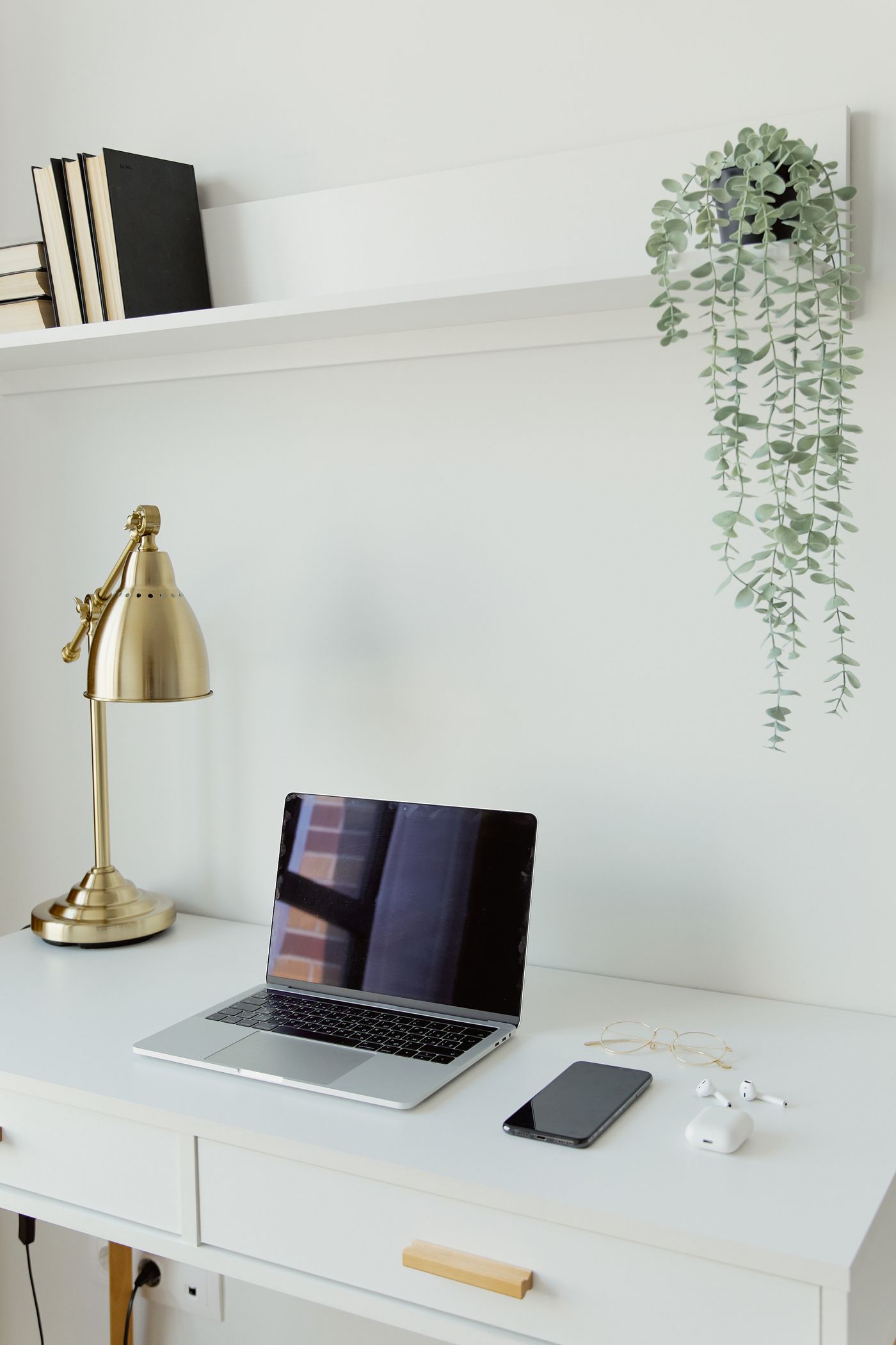 Minimal workspace with a laptop, phone and brass desk lamp